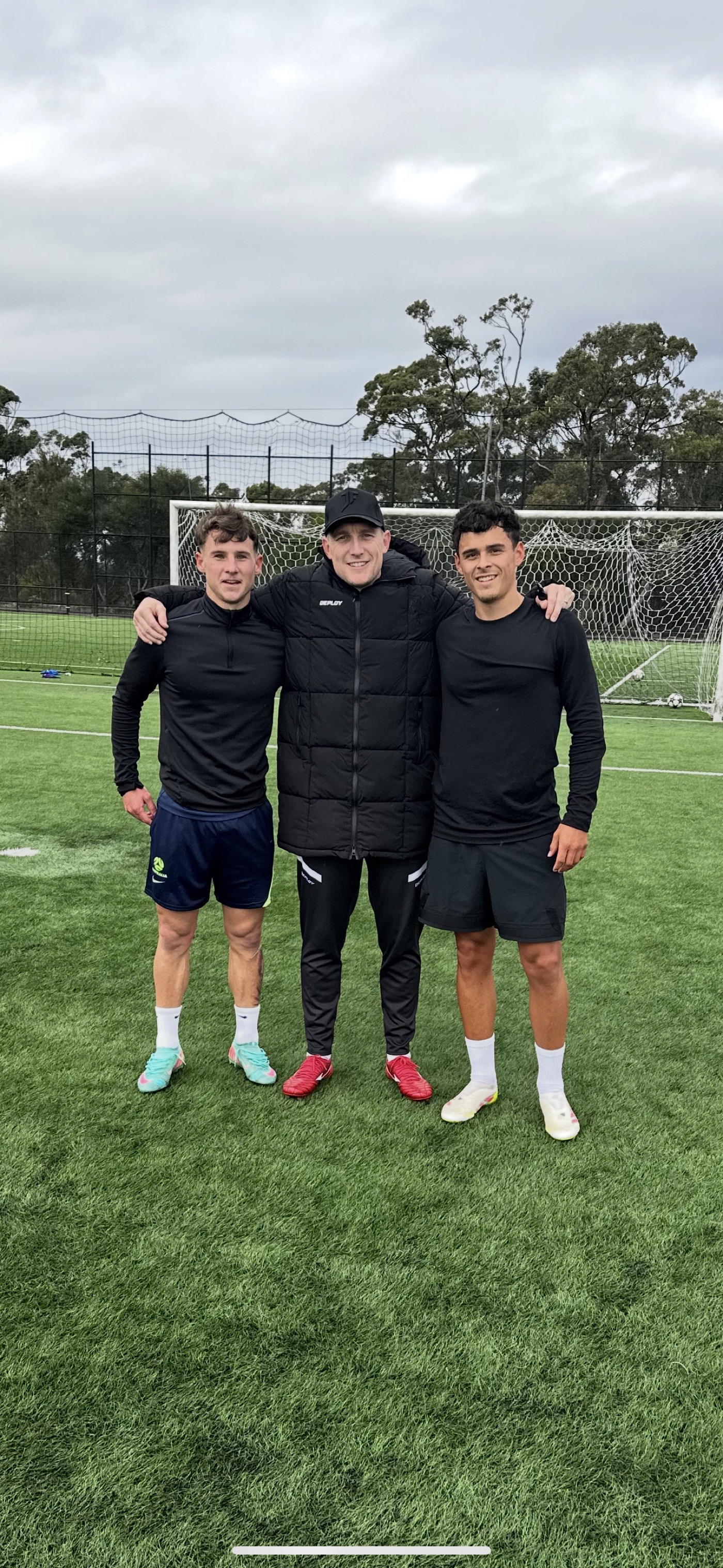 Lee with two young professional players on a Sydney pitch